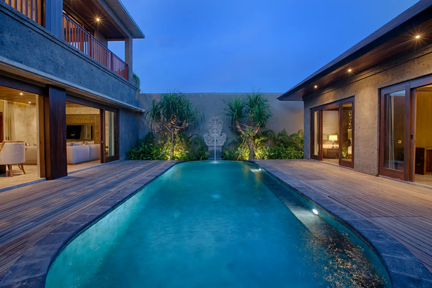 Foto eksterior villa Bali malam hari dengan pencahayaan warm tone premium yang menonjolkan arsitektur dan kolam renang